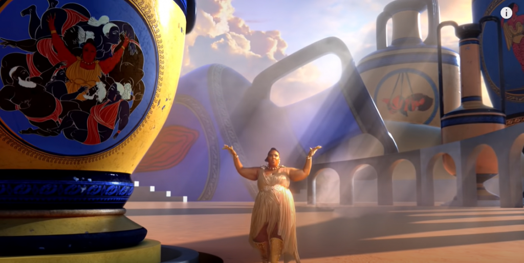 Lizzo in Rumors music video, in golen dress, surrounded by oversized Greek vases and arches reminiscent of Roman aqueducts